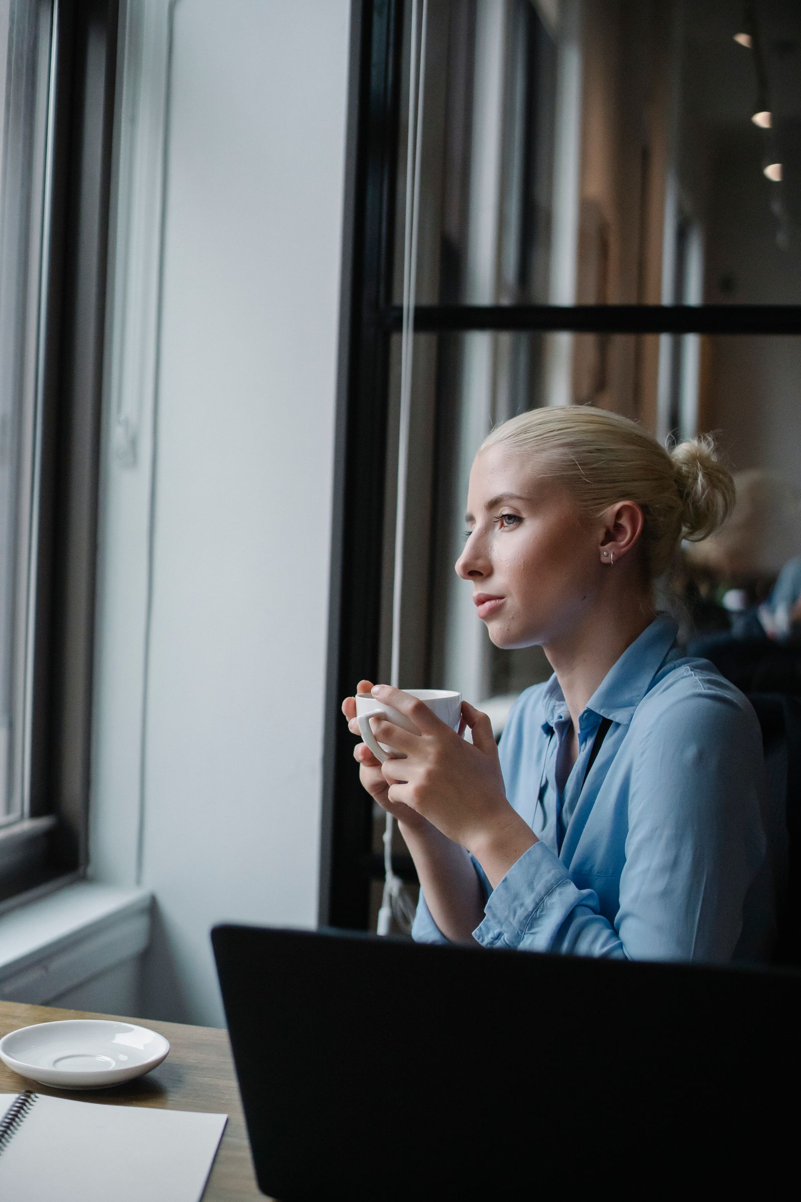 An employee pausing at their desk with a cup of tea, looking out of the window
